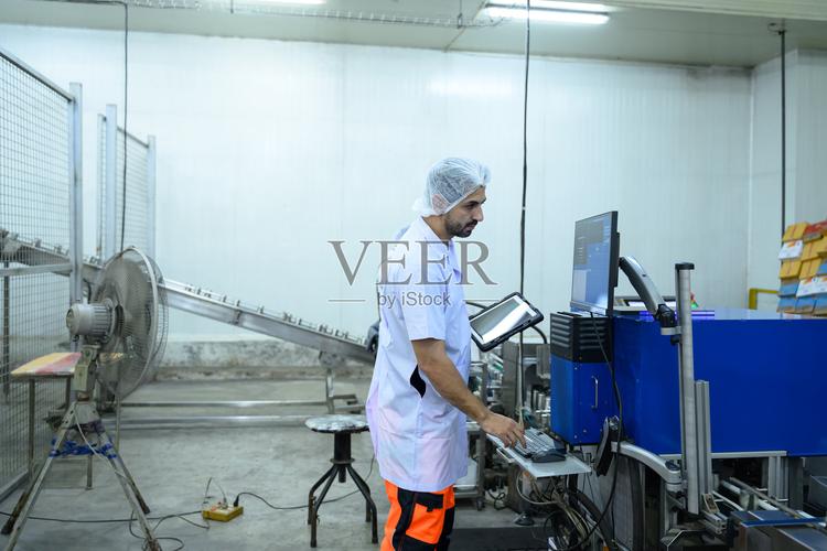 现代制造业中,食品工厂工人通过计算机系统操作机器